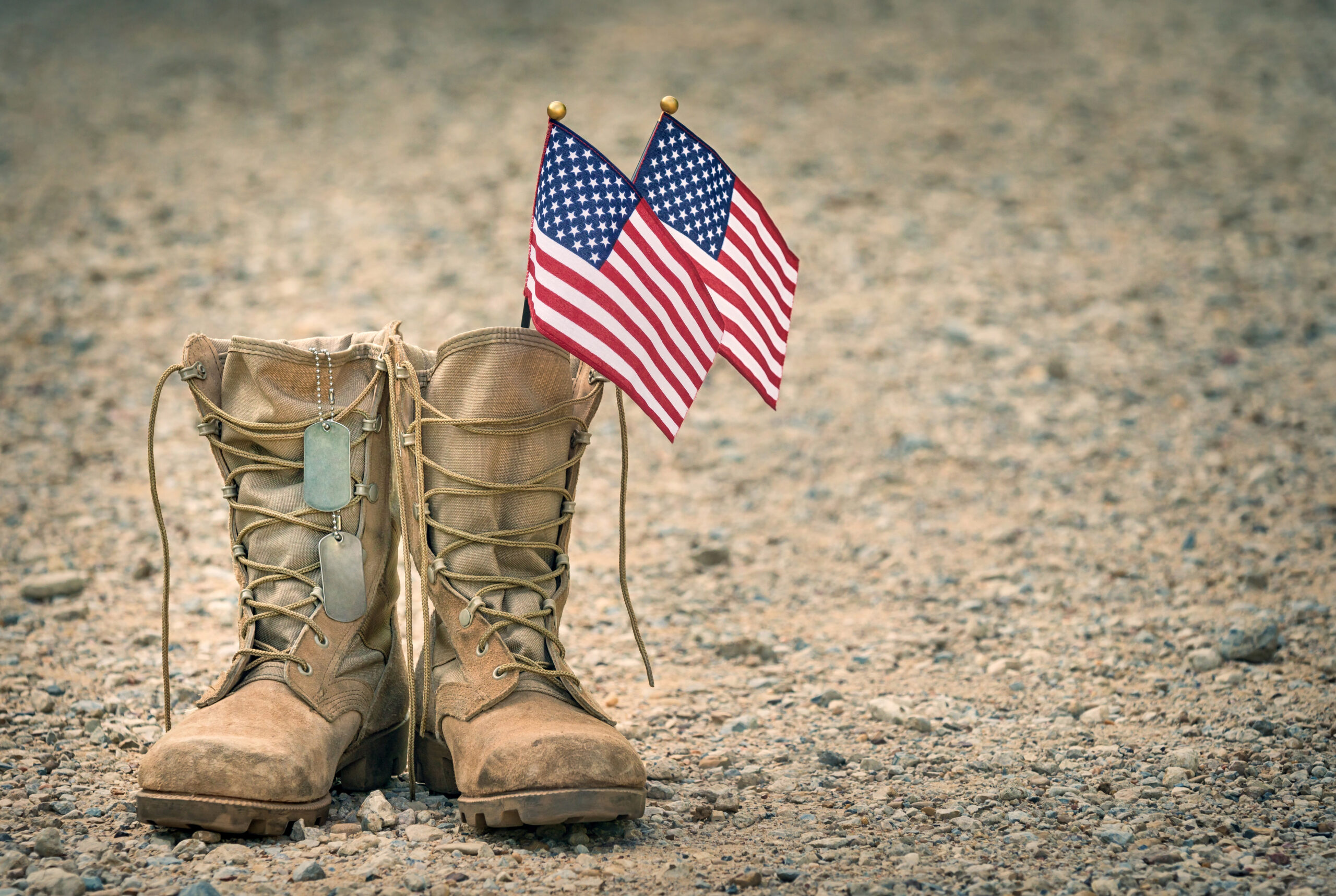 Old military combat boots with dog tags and two small American flags